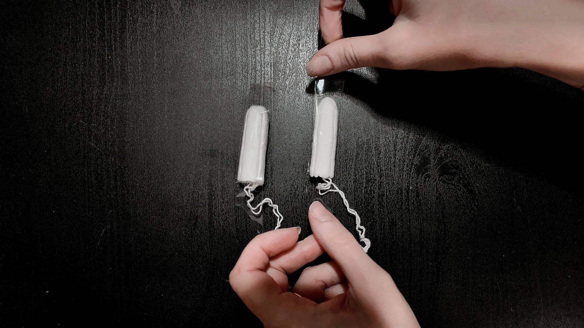 Applying adhesive tape to two tampons placed side by side.